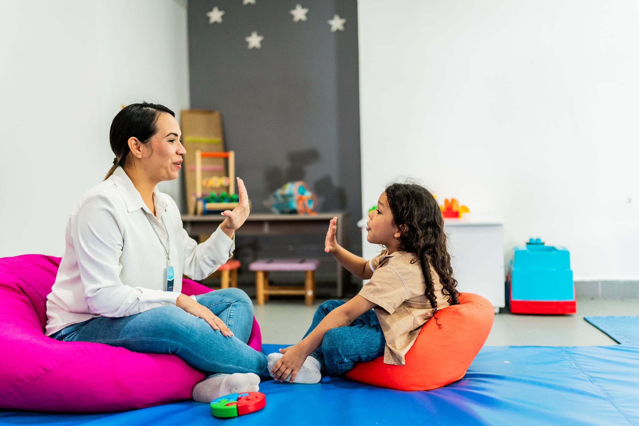 Mid adult psychotherapist woman talking to child boy at playroom
